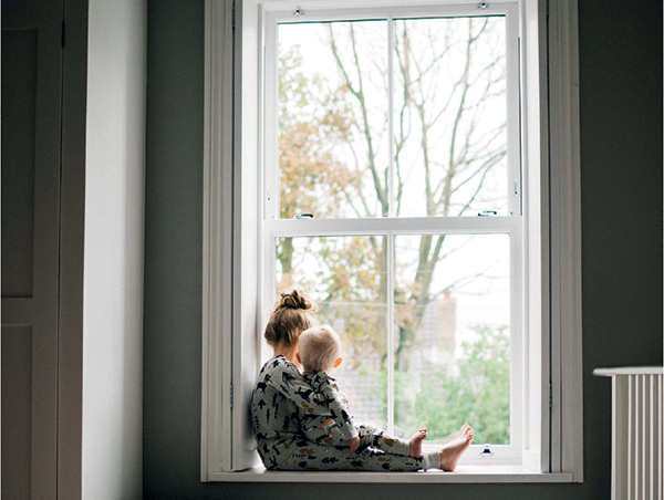 Child looking out the window sitting on the windowsill
